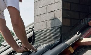 Fot. 10. Taśmę do tzw. miękkiej obróbki komina należy nakleić tak, by mocno zachodziła na dachówki i dobrze docisnąć do powierzchni pokrycia. Dachówki muszą być czyste – wolne od pyłu i tłuszczu. 
